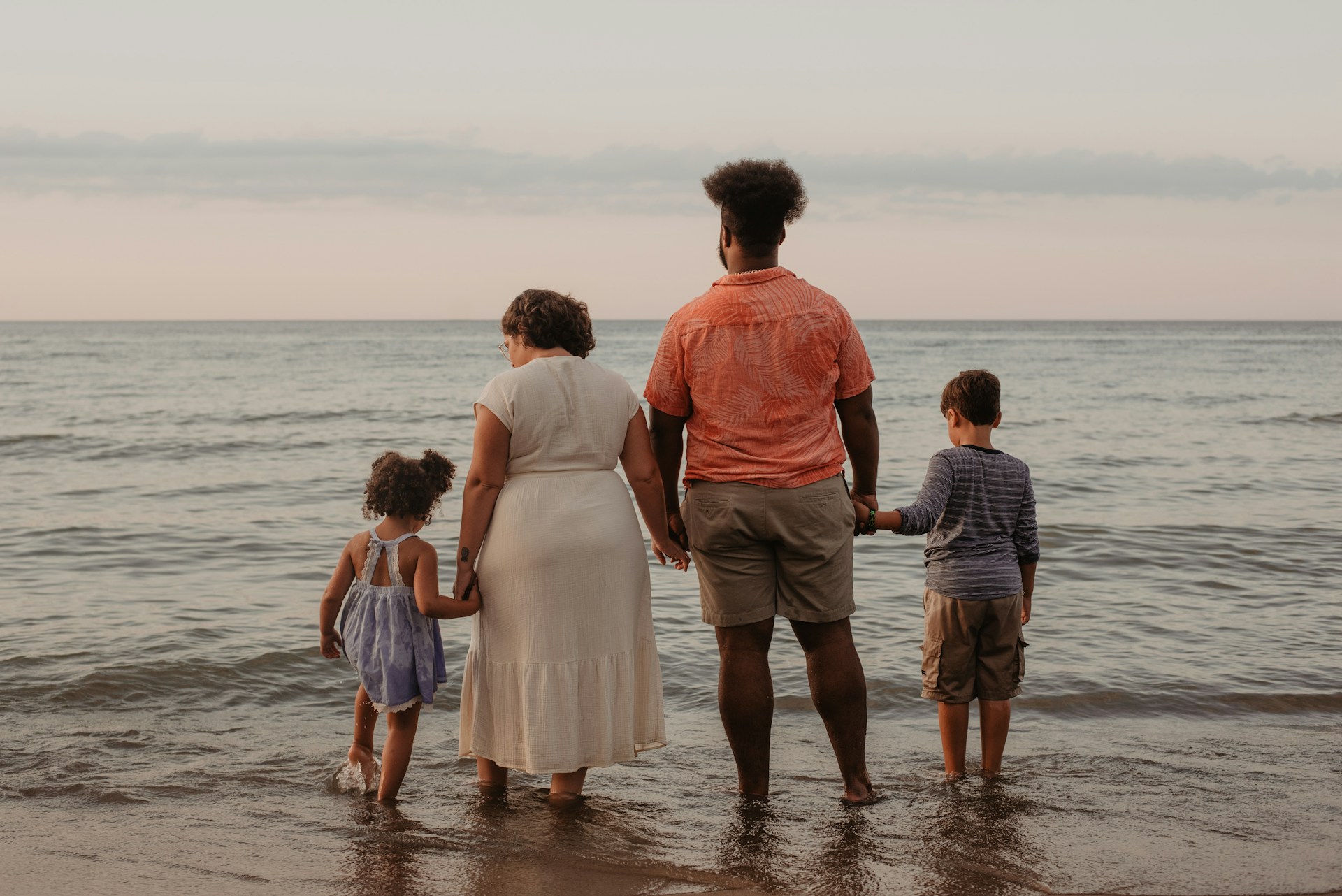 Family of four holdings hands at the beach
